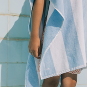 Kid wrapped in a blue and white poncho by a pool.