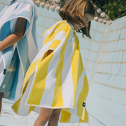 Two kids wearing colorful ponchos by a poolside.