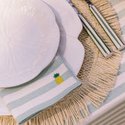 Napkin with pineapple design on a table setting with plates and cutlery.