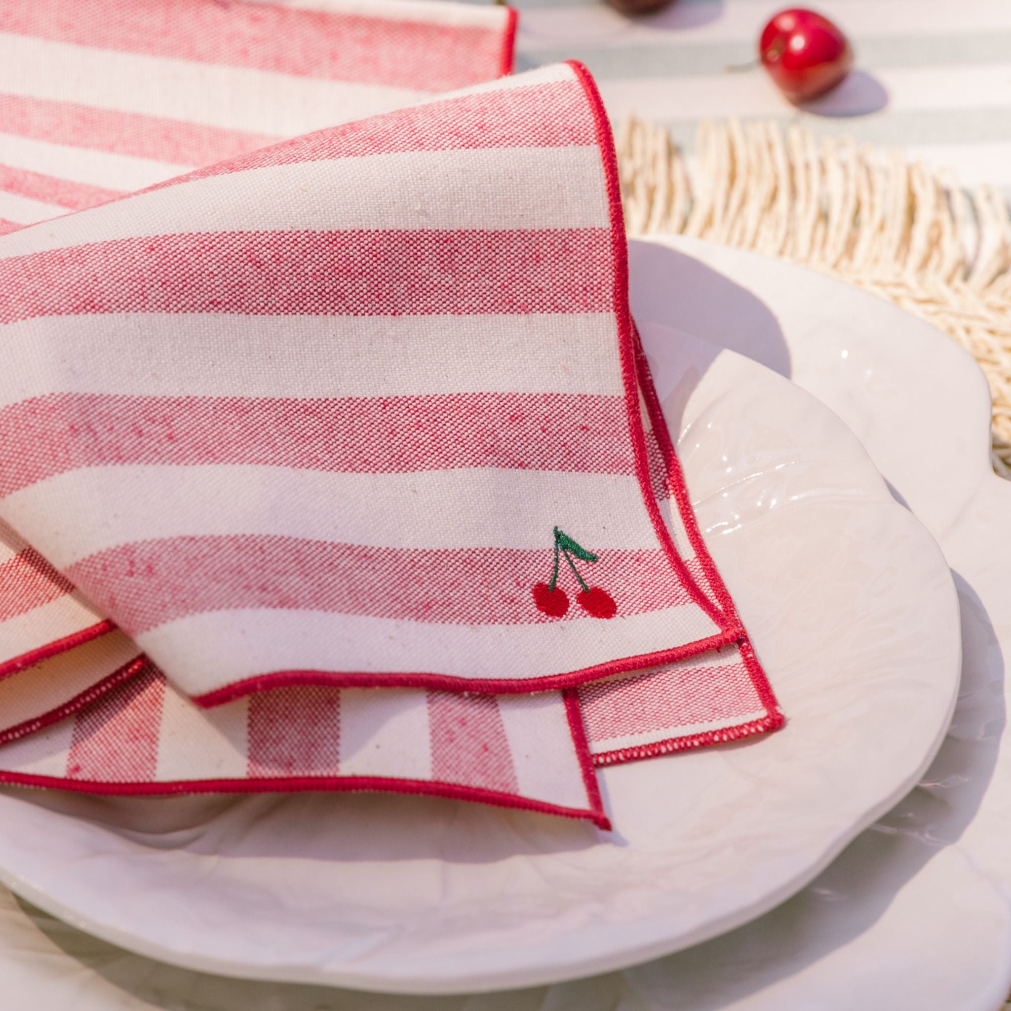 Red and white striped napkin with cherry design on a white plate